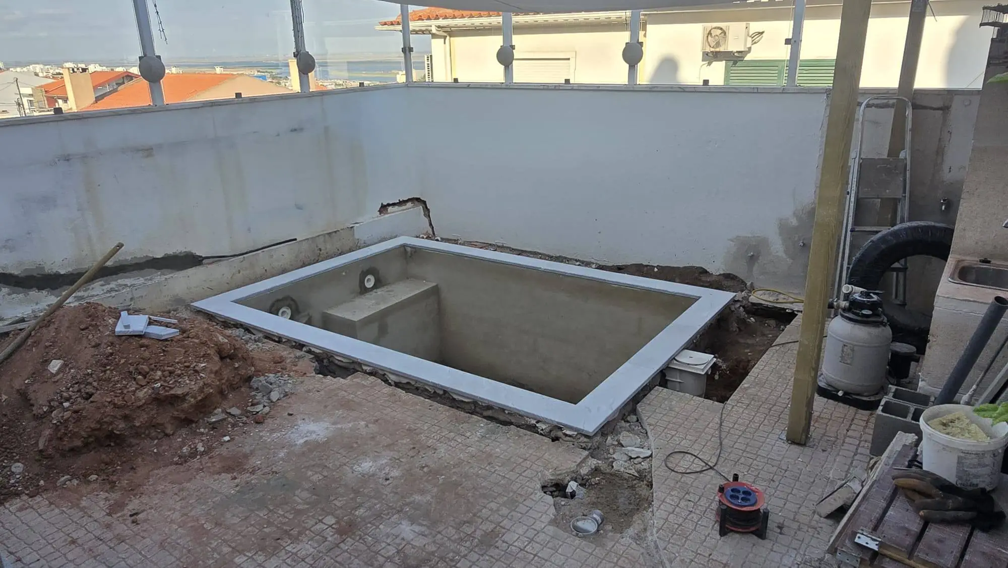Estrutura da piscina em construção, com a vista do terraço por trás